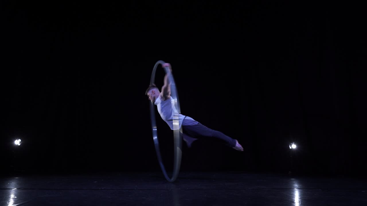 el intérprete de la rueda cyr muestra trucos en un escenario negro con humo