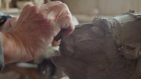 elderly sculptor creating clay head in workshop