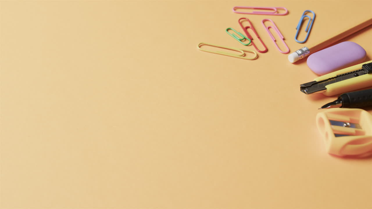 primer plano de papelería escolar colorida con espacio de copia en fondo beige, en cámara lenta