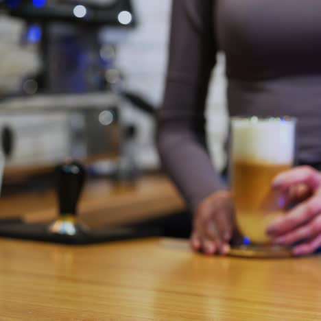 cappuccino or latte in glass. woman puts drink from coffee machine. fresh coffee with whipped cream in tall clear glass on table. close-up.