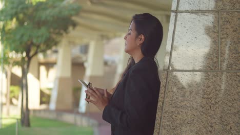 Young-woman-enjoying-her-lunch-break-in-the-city-while-looking-at-her-tablet-device-wearing-business-attire