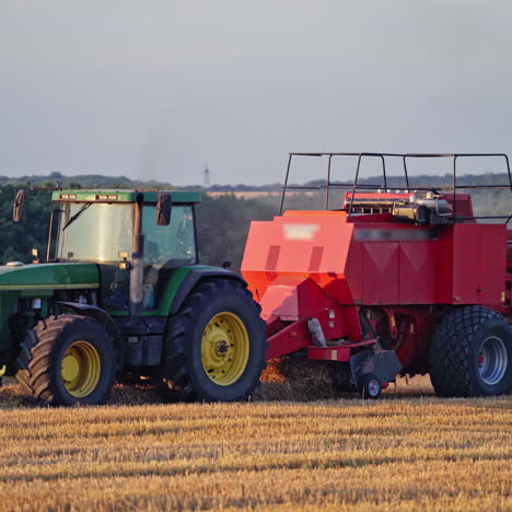 modern tractor collects dry grass and pressing it into bale. agricultural process of gathering hay on the golden field. close-up.