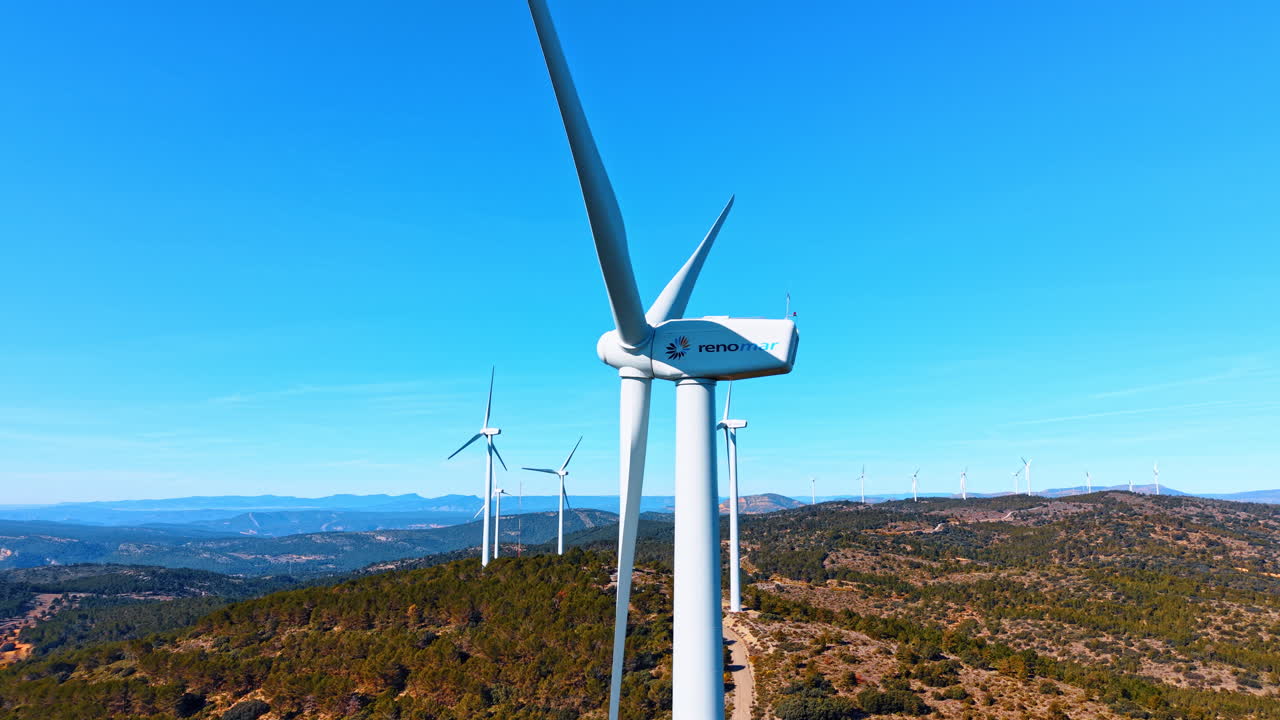 Alicante, Espanha, 8 de agosto de 2025: Close-up da nacele de uma turbina eólica com o logótipo Renomar. Gerador eólico moderno num cume arborizado contra o céu azul para energia sustentável.
