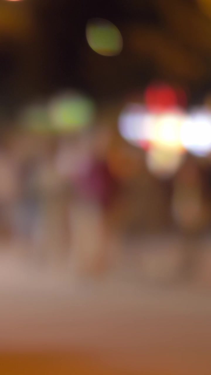 Illuminated night street with walking people, defocus