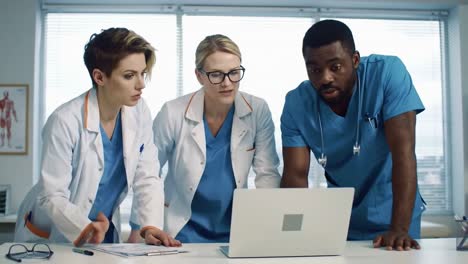 multiethnic medical team collaborating around a laptop in a hospital office