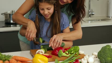 Madre-Mostrando-A-Su-Hija-Cómo-Cortar-Verduras