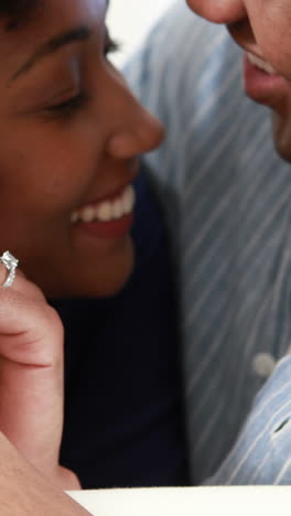 una joven pareja sonriente abrazándose en el sofá