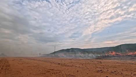 laborer use drip torch to set fire to vegetation creating a firebreak, low pov