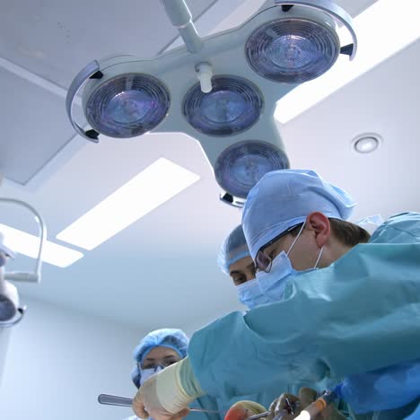group of doctors perform an operation to a patient. surgeons in medical uniform and masks working in the operating room
