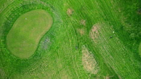 top shot of a golfer shooting a chip shot towards the green, overshooting