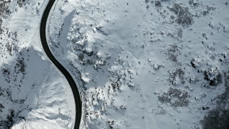 Eine-Kurvenreiche-Straße-In-Einer-Verschneiten-Landschaft,-Aufgenommen-Bei-Hellem-Tageslicht,-Luftaufnahme