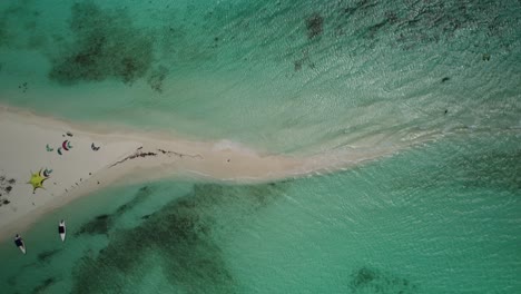 A-sandbar-in-turquoise-waters-with-boats-and-beachgoers-on-a-sunny-day,-aerial-view