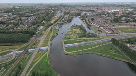 wide zoom out view of a canal crossing the highway at a height under daylight in netherlands