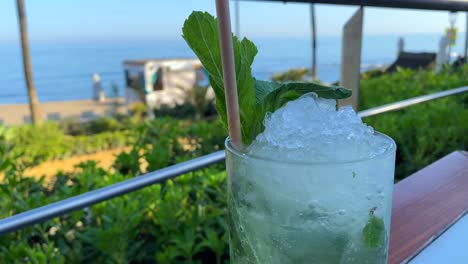 delicious fresh cold mojito cocktail at a beautiful beach bar with sea view, refreshing drink, enjoying summer with dreamy holiday in marbella spain, vacation destination, 4k shot