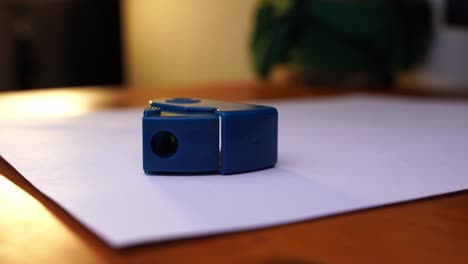 dark blue sharpener is placed on a white paper on a wooden desk