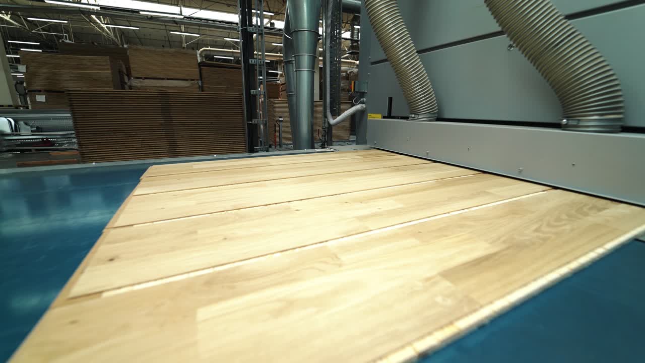 Modern parquet grinding technology at a woodworking factory. The process of processing uneven boards. Line of manufacturing. Close-up