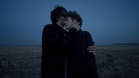 romantic couple embracing tenderly in open field at twilight
