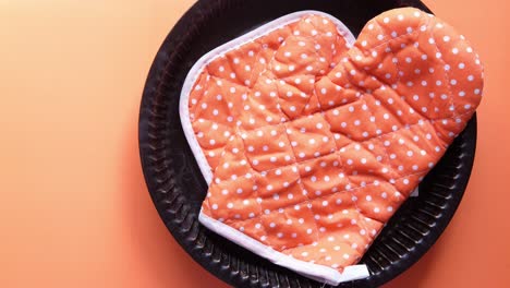 orange dotted oven mitts on dark dish