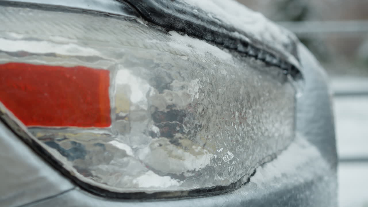 얼음과 눈으로 인 차의 얼음 뒷등의 클로즈업, 복잡한 얼음 패턴과 차량 표면에 겨울의 냉각 효과를 강조합니다.