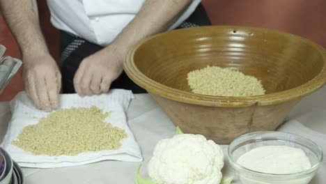 las manos extendidas couscous al vapor caliente en la tela receta tradicional africana, detalle disparado