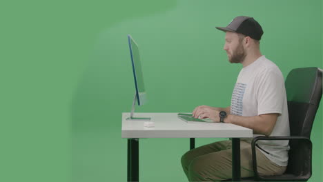 joven desarrollador que usa una computadora para escribir código en su computadora de escritorio en el estudio de pantalla verde