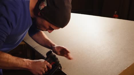 carpenter using nail gun to assemble a panel