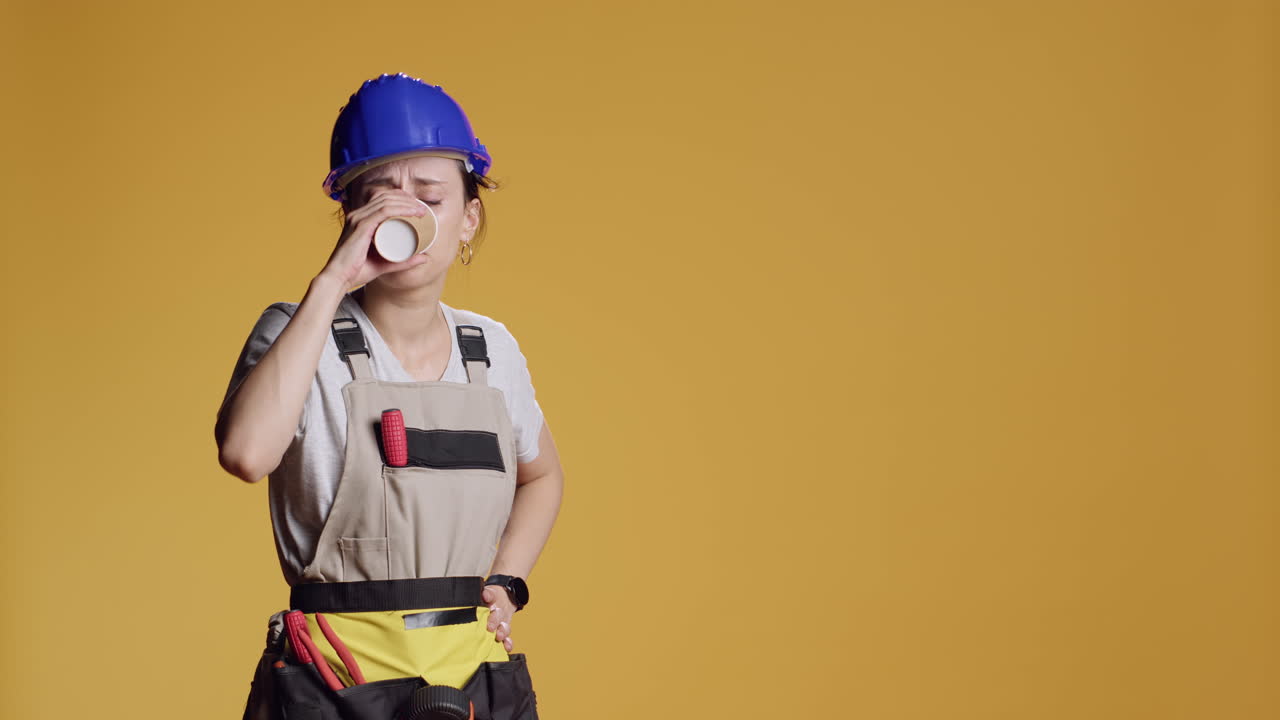 Portrait of sleepy handywoman drinking coffee cup at building work