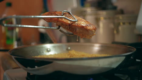 pechuga de pollo a la parrilla goteando jugos salados sobre una sartén llena de cuscús a fuego lento - cámara lenta