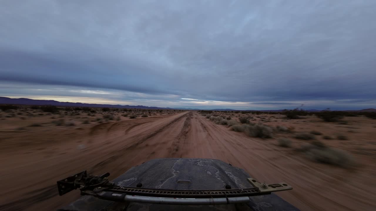 차량의 햇빛에 손상된 후드가 보이는 모하비 사막의 험준한 지형을 통해 속도를 내는 오프로드 차량 - 하이퍼 랩스