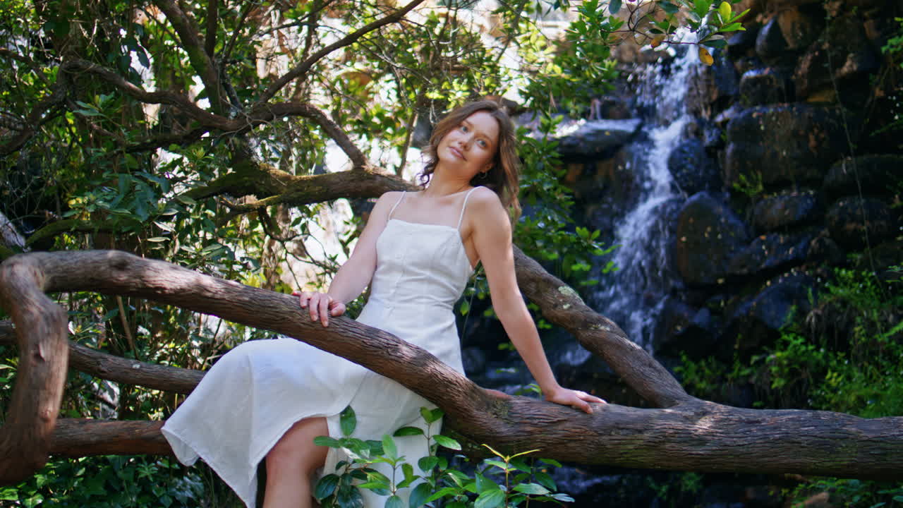 Romantic woman sitting tree resting alone. Dreamy girl looking camera at forest
