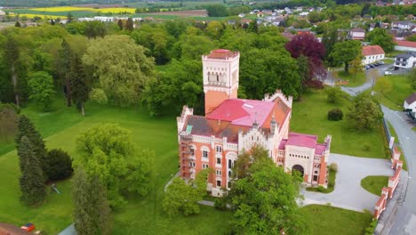 Ikonisches-Schloss-Rotenturm-Im-österreichischen-Burgenland-Mit-Großer-Grüner-Wiese-Am-Waldrand,-Luftaufnahme