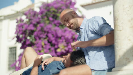 gay man lying on his lover's knees in public garden