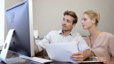 Business-people-looking-at-files-and-working-on-computer