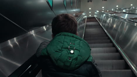 boy moving up on escalator in subway