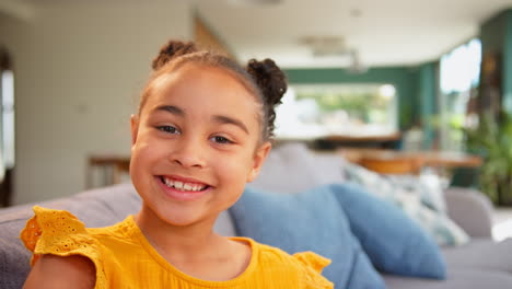 Portrait-Of-Smiling-Girl-Relaxing-Sitting-On-Sofa-At-Home