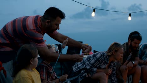 people frying sausages on campfire traveling together