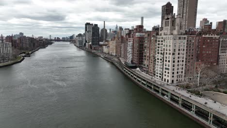 una vista aérea sobre el río este con la isla de roosevelt a la izquierda y el lado este de manhattan a la derecha, tomada en un día nublado