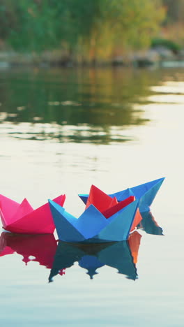 paper boats on the water. colored paper ships in the water vertical video