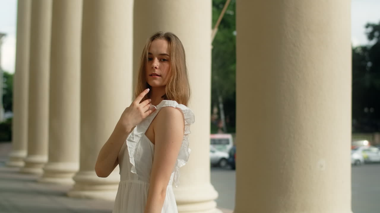 Woman in white dress posing under columns