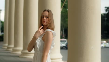 woman in white dress posing under columns