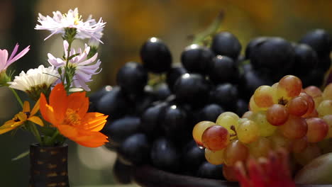 Pan-right-from-flowers-to-assorted-fresh-ripe-grapes-in-bowl