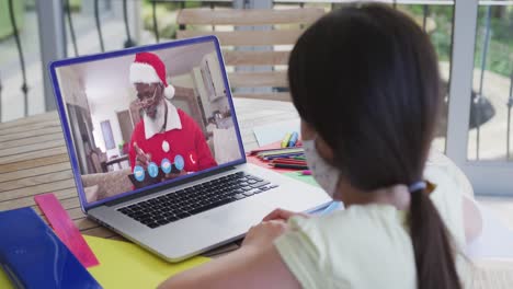 Chica-Caucásica-Con-Mascarilla-En-El-Chat-De-Vídeo-Portátil-Durante-La-Navidad-En-Casa