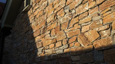 parallax movement as sunset golden hour light hitting the side of a rustic stone walled building casting harsh shadows with luxury feel