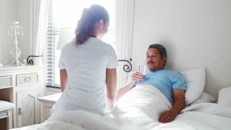 doctora dando un vaso de agua a un hombre mayor 4k