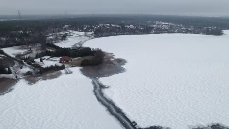 Panoramic-aerial-overview-above-rural-town-and-snow-covered-lake-near-Suwalki-Gap-Masuria-Poland