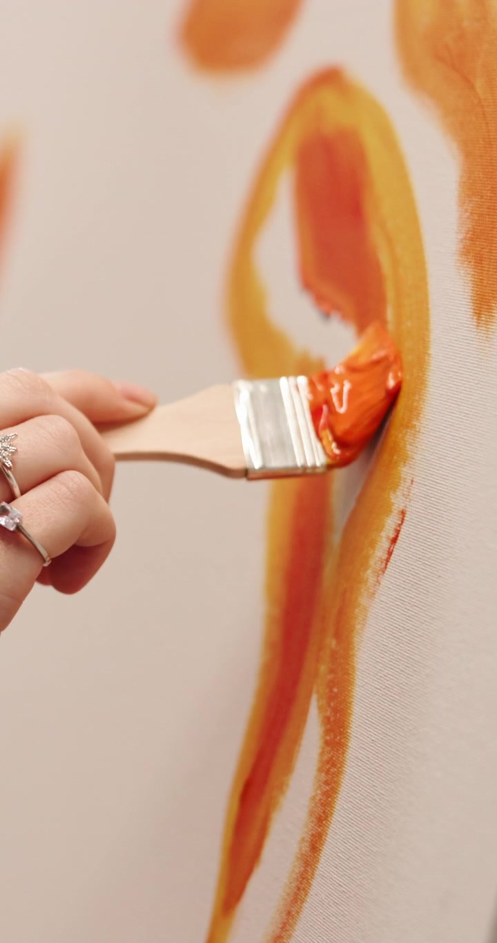 Artista che dipinge forme astratte arancioni su tela