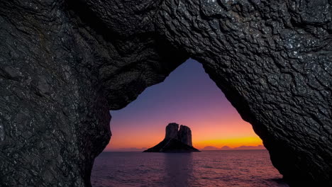 dramatic sunset over sea stacks viewed from a coastal cave archway