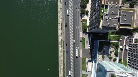 cars driving along street between seine river and modern neighborhood of paris in france