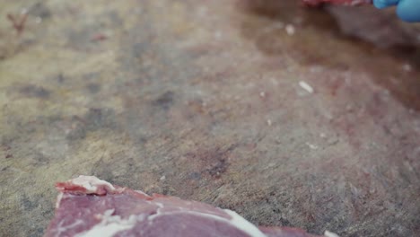 close-up of a butcher placing down a prime cut of rib steak