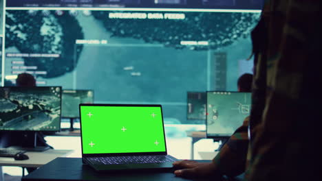 Commander-examines-a-greenscreen-on-laptop-in-military-command-center